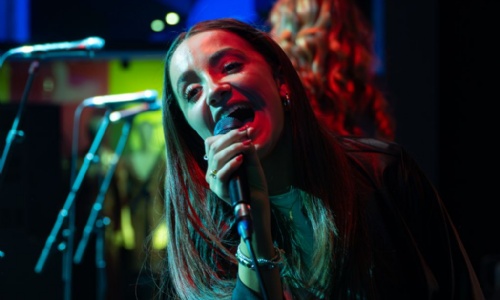Student singing with a microphone in their hand at a performance on stage